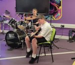 Two boys playing drums and guitar