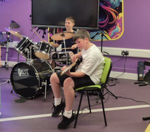 Two boys playing drums and guitar